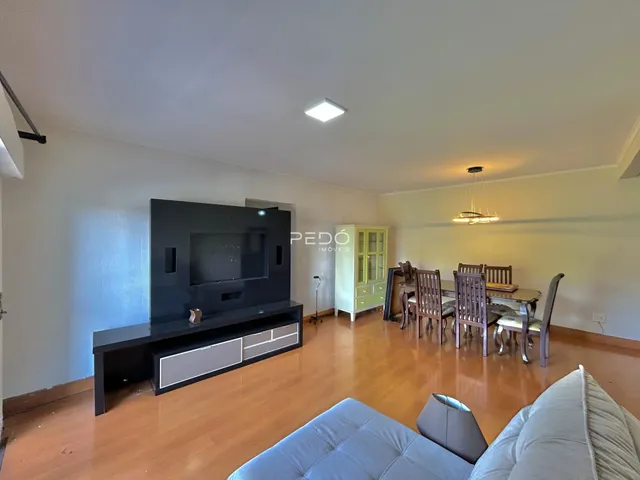 Ambiente interno de uma sala de estar com piso de madeira e área de jantar.