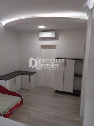 Foto de uma sala com piso de madeira e armários embutidos.