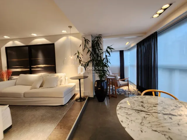 Sala de estar moderna com sofá branco e piso de madeira clara.