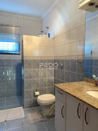 Foto de um banheiro com revestimento de azulejos e box de vidro.