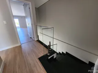 Hall de entrada com piso de madeira e divisória de vidro.