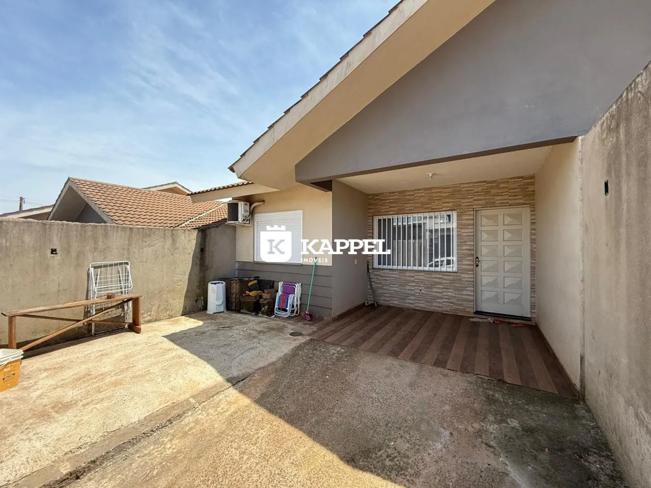 Fachada externa de uma residência com piso de madeira e área externa.