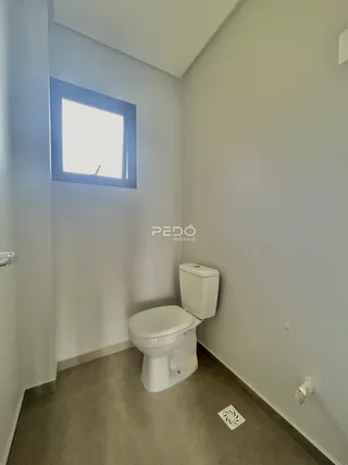 Foto de um banheiro estreito com janela e vaso sanitário branco.
