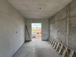 Interior de um espaço com paredes de concreto cru e piso de concreto.