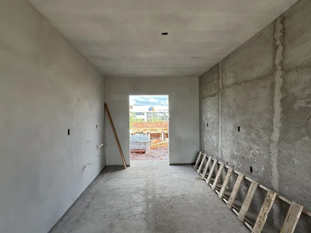 Interior de um espaço com paredes de concreto cru e piso de concreto.