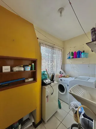 Imagem de uma área de serviço com máquina de lavar e pia em um imóvel no Brasil.