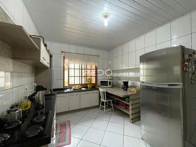 Foto de uma cozinha com armários brancos e piso cerâmico.