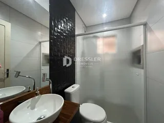 Interior de um banheiro com pias e box de vidro.