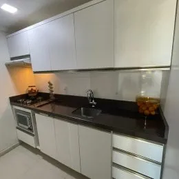 Foto de uma cozinha com armários brancos e bancadas escuras.