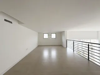 Ambiente interno de uma sala ampla com piso claro e vista da cidade.