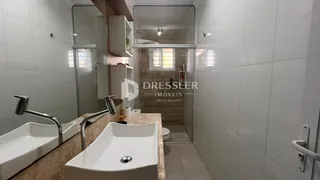 Banheiro com pias duplas e revestimento branco.
