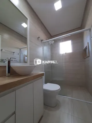 Banheiro com bancada de mármore e box de vidro transparente.