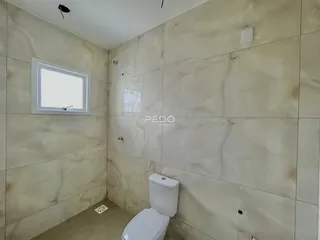 Foto de um banheiro com paredes revestidas de pedra clara e piso bege.