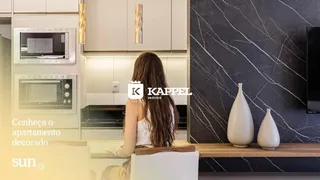 Vista da cozinha decorada com armários brancos e eletrodomésticos em um apartamento.
