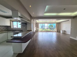 Sala de estar com piso de madeira e bancada da cozinha visíveis.