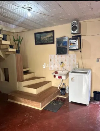 Interior da sala com escadaria e área de cozinha antiga.