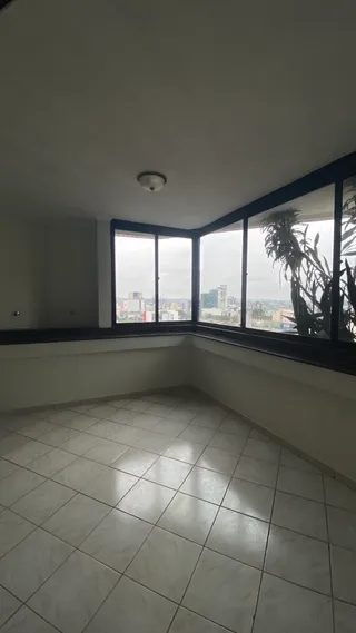 Vista interna de um cômodo com piso de cerâmica e grandes janelas.