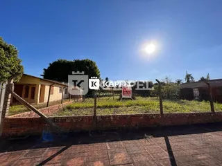 Foto da fachada de uma residência com muro de tijolos e gramado sob luz solar intensa.