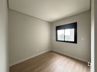 Ambiente interno com piso de madeira e janela de vista para a cidade.