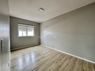 Sala de estar com piso de madeira clara e janela.