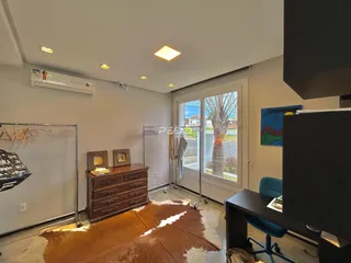 Ambiente interno de uma sala com piso de madeira e grandes portas de vidro.