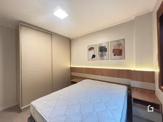 Quarto moderno com cabeceira de madeira e armários embutidos.