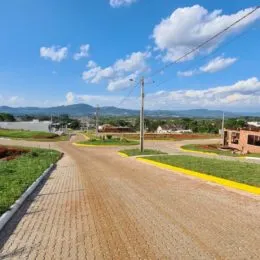 Vista de uma estrada pavimentada em uma área com colinas ao fundo.
