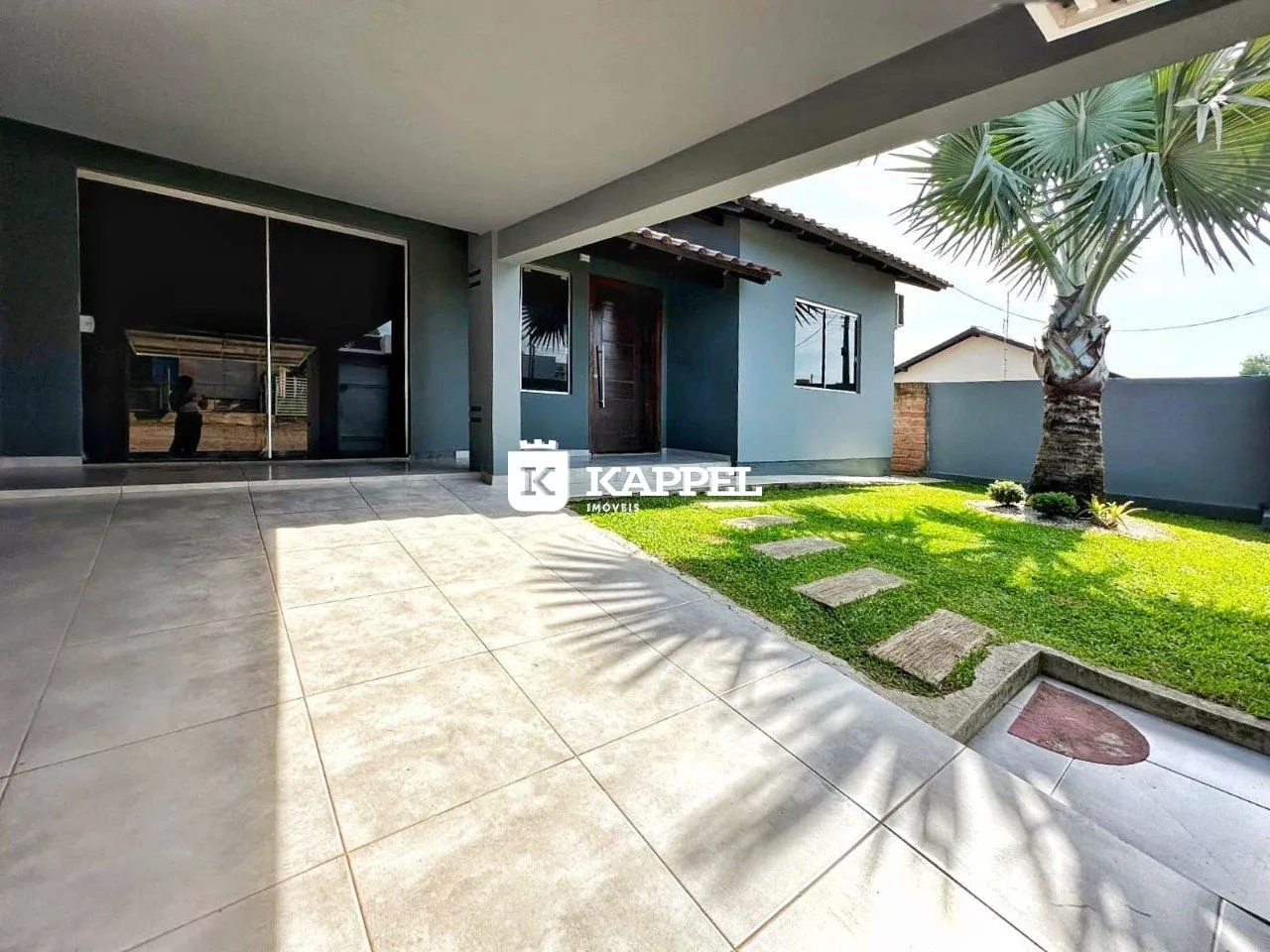 Vista externa da propriedade mostrando a área de lazer e o jardim com palmeira.