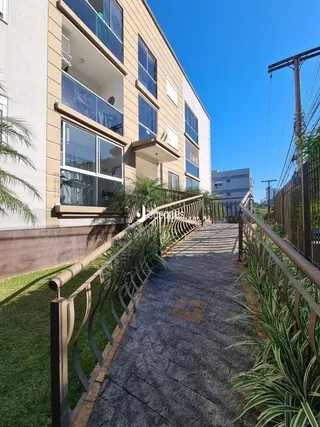 Vista de um caminho externo com grade e vegetação em uma propriedade.
