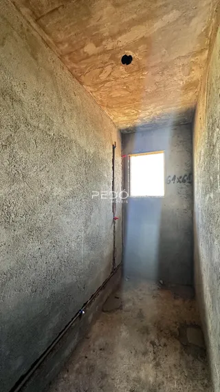 Corredor interno com paredes de alvenaria e piso de concreto.