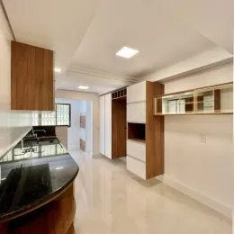 Foto interna de uma cozinha com armários de madeira e piso claro.