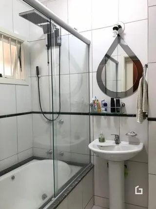 Foto de um banheiro com box de vidro e banheira.