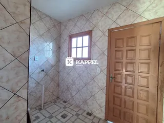Foto interna de um banheiro com revestimento de azulejos claros.