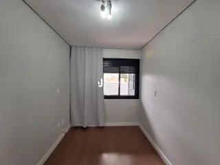 Vista interna de um cômodo com piso de madeira e paredes brancas.