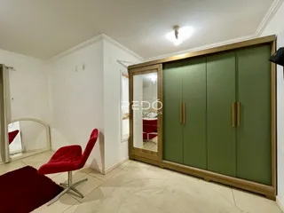 Interior de um cômodo com armário de madeira verde e decoração vermelha.