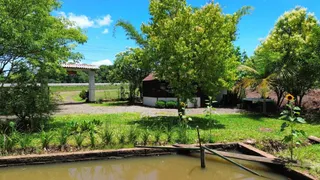 Paisagem externa com vegetação exuberante e um pequeno corpo d'água em um ambiente rural.