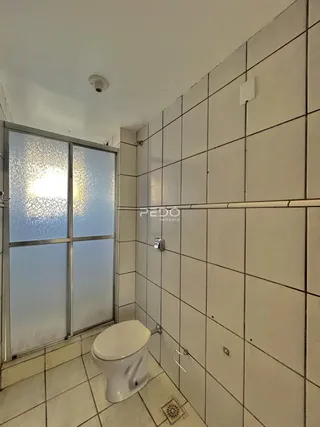 Foto de um banheiro com piso de cerâmica e paredes revestidas de azulejos brancos.