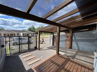Foto de uma área externa coberta com piso de madeira e estrutura de madeira.