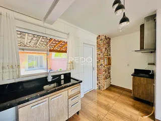 Vista interna de uma cozinha com piso de madeira e janela para o exterior.