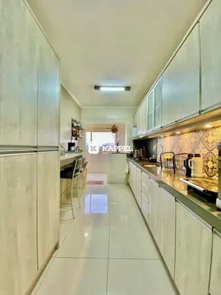 Uma cozinha moderna com armários brancos e piso claro.
