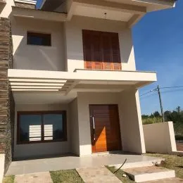 Fachada de uma casa moderna em Lajeado, Brasil com revestimento claro.