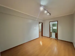 Hall de corredor com piso de madeira e paredes brancas.