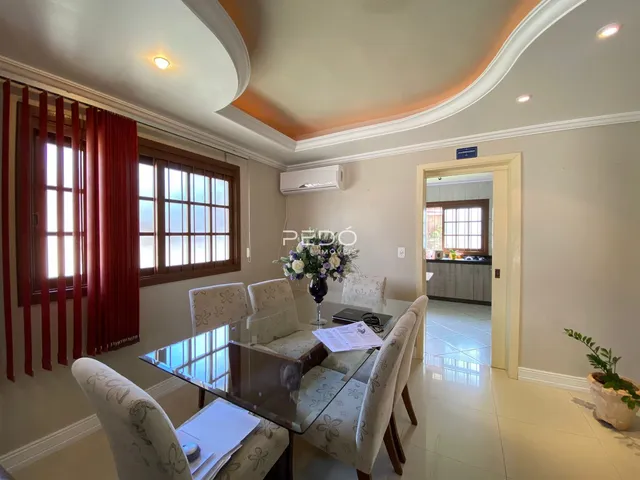 Sala de jantar com grandes janelas e decoração clara.