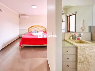 Quarto com cama de cabeceira dourada e roupa de cama vermelha.