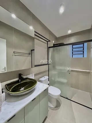 Banheiro moderno com box de vidro e pia de mármore.