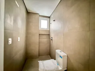 Foto de um banheiro interno com paredes bege e um vaso sanitário branco.