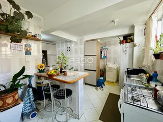 Interior de uma cozinha e área de jantar com piso cerâmico e armários brancos.