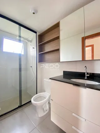 Foto de um banheiro com box de vidro e louças brancas.