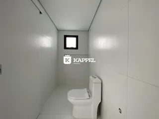 Foto de um corredor com um vaso sanitário branco em um imóvel.