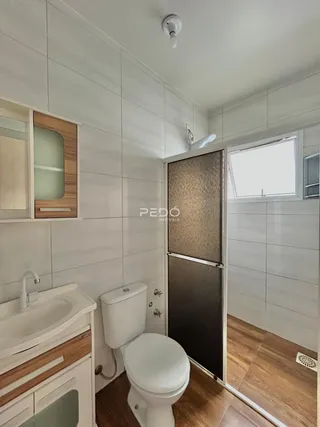 Foto de um banheiro com revestimento branco e piso de madeira.
